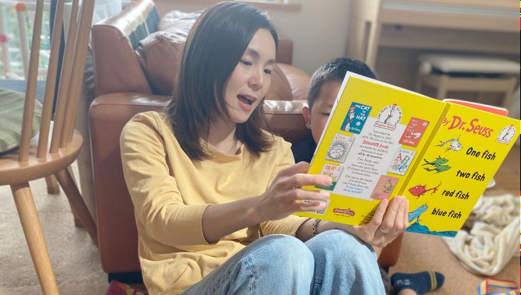 絵本を読み聞かせるお母さんと、隣で聞き入る男の子
